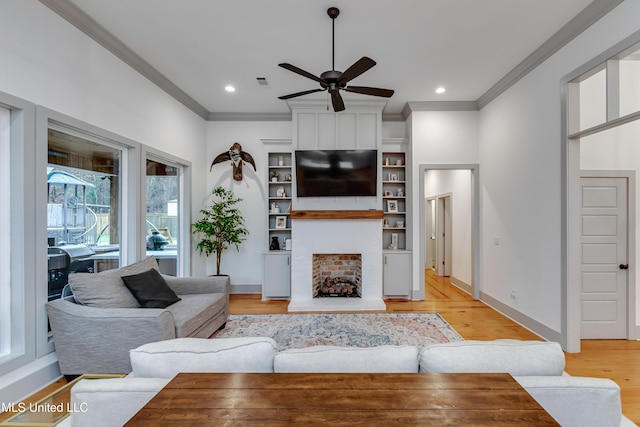 living room with ceiling fan, a fireplace, crown molding, and light hardwood / wood-style flooring