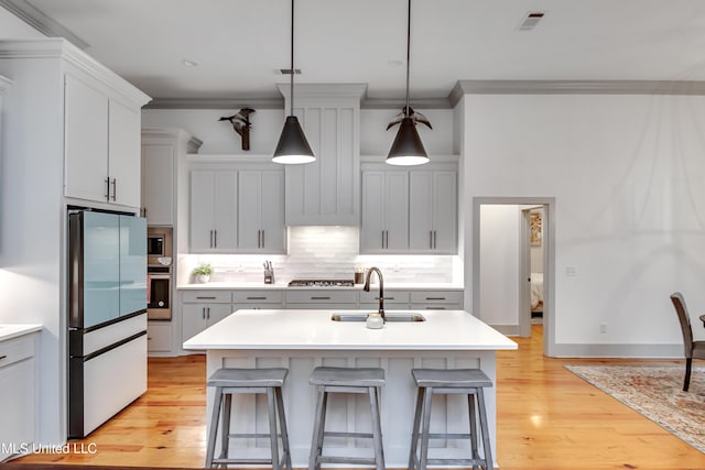 kitchen with decorative light fixtures, appliances with stainless steel finishes, and a center island with sink