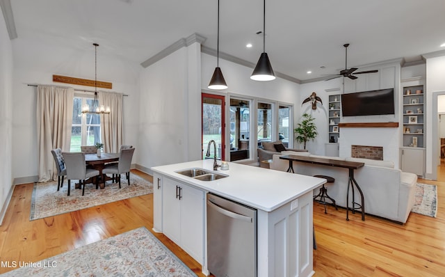 kitchen featuring dishwasher, a center island with sink, sink, hanging light fixtures, and white cabinets