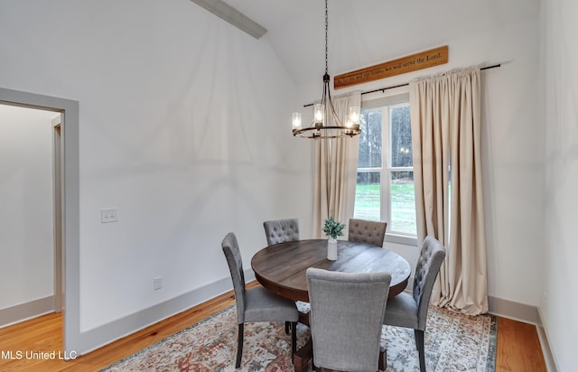 dining area with an inviting chandelier, lofted ceiling, and hardwood / wood-style flooring