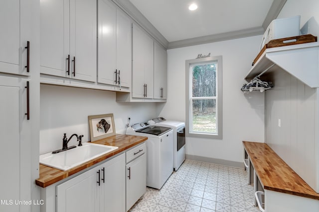 laundry area featuring cabinets, ornamental molding, washer and clothes dryer, and sink