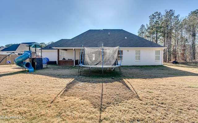 back of house featuring a trampoline, a yard, and a playground