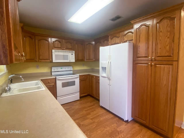 kitchen featuring sink, light hardwood / wood-style flooring, and white appliances