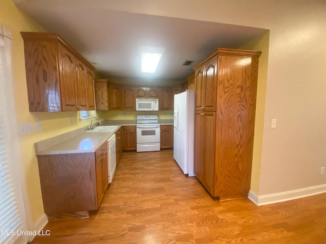 kitchen featuring white appliances, light hardwood / wood-style floors, and sink