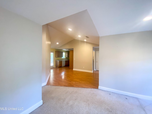 empty room with light hardwood / wood-style flooring and lofted ceiling