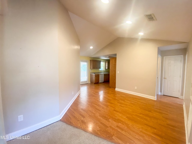 spare room with lofted ceiling and light wood-type flooring