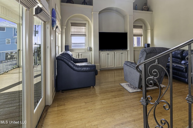 living room with light wood-type flooring, arched walkways, and a towering ceiling