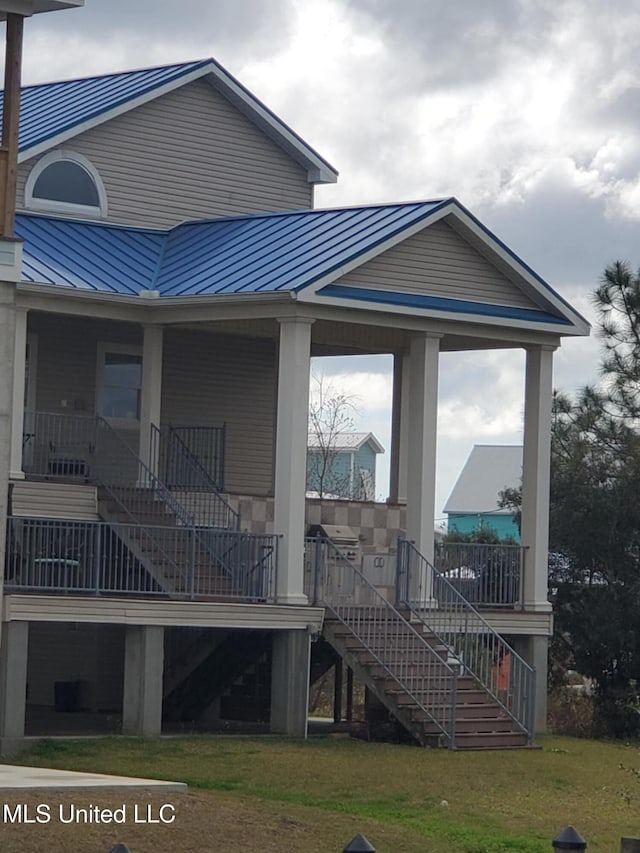 exterior space with a standing seam roof, stairway, metal roof, and a yard