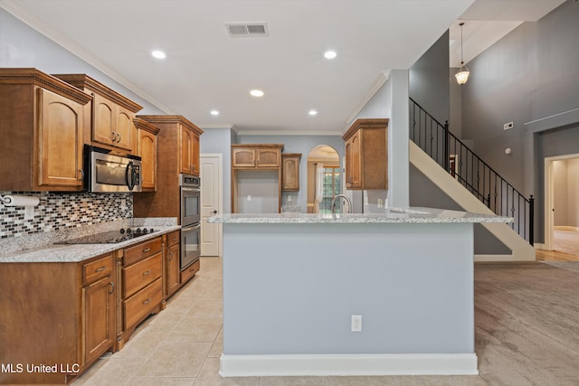 kitchen featuring light stone countertops, backsplash, stainless steel appliances, crown molding, and light tile patterned floors