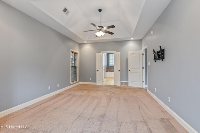 spare room with light colored carpet, a raised ceiling, ceiling fan, and lofted ceiling