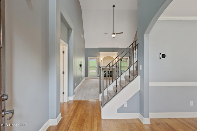 entryway featuring hardwood / wood-style flooring, ceiling fan, crown molding, and high vaulted ceiling