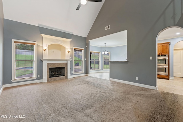 unfurnished living room with light carpet, high vaulted ceiling, a fireplace, and ornamental molding