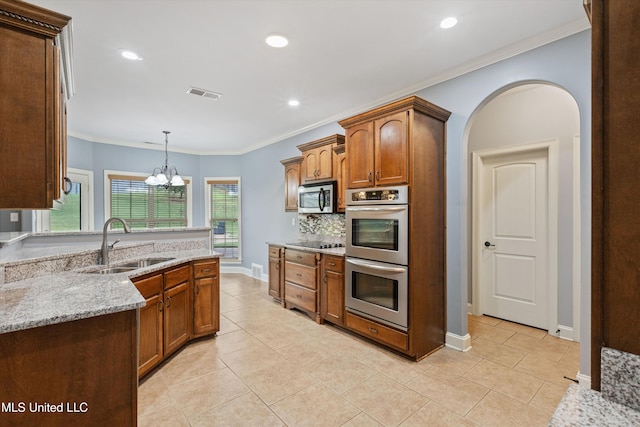 kitchen featuring appliances with stainless steel finishes, light stone counters, sink, an inviting chandelier, and hanging light fixtures