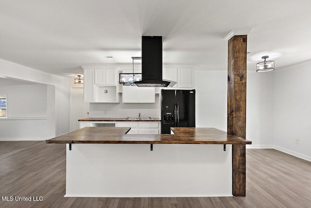 203 Bruin Ave, Pearl, MS 39208 - kitchen with black refrigerator with ice dispenser, wall chimney range hood, wood finished floors, and white cabinetry