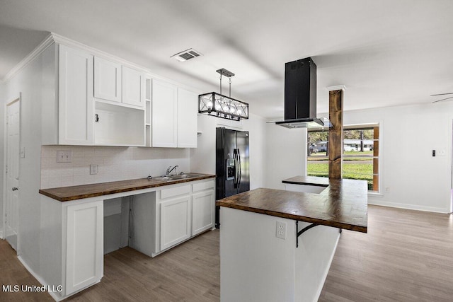203 Bruin Ave, Pearl, MS 39208 - kitchen with butcher block counters, island range hood, light wood-type flooring, black fridge, and a sink