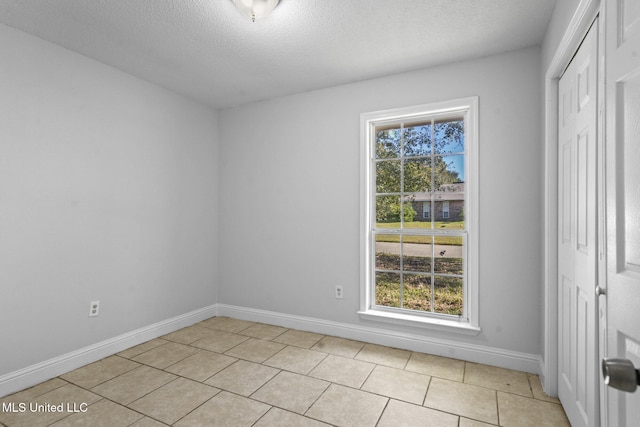 spare room with light tile patterned flooring and a textured ceiling