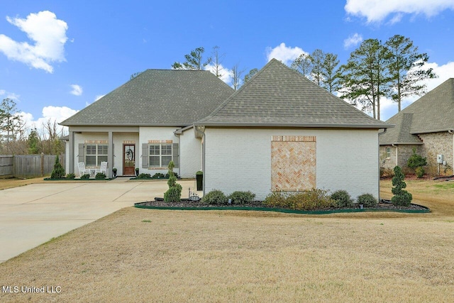 view of front facade with a front lawn, fence, and roof with shingles