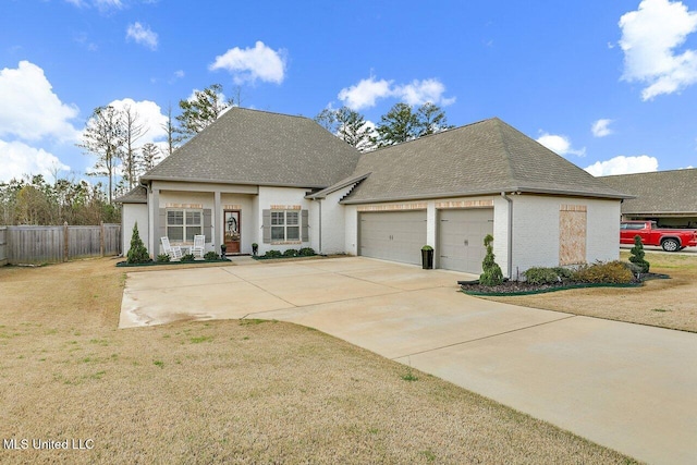 view of front of property featuring a front lawn, driveway, fence, a shingled roof, and a garage