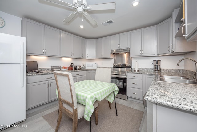 kitchen with white appliances, sink, ceiling fan, gray cabinets, and light wood-type flooring