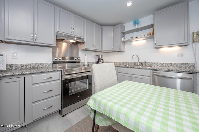 kitchen featuring gray cabinets, stainless steel appliances, light stone counters, and sink