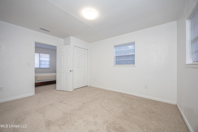 unfurnished bedroom with a closet and light colored carpet