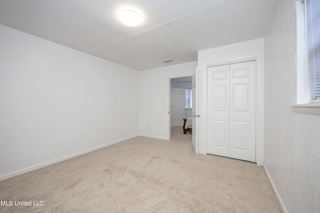 unfurnished bedroom featuring light colored carpet and a closet