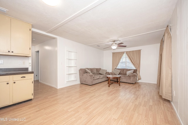 living room featuring a textured ceiling, light hardwood / wood-style flooring, and ceiling fan