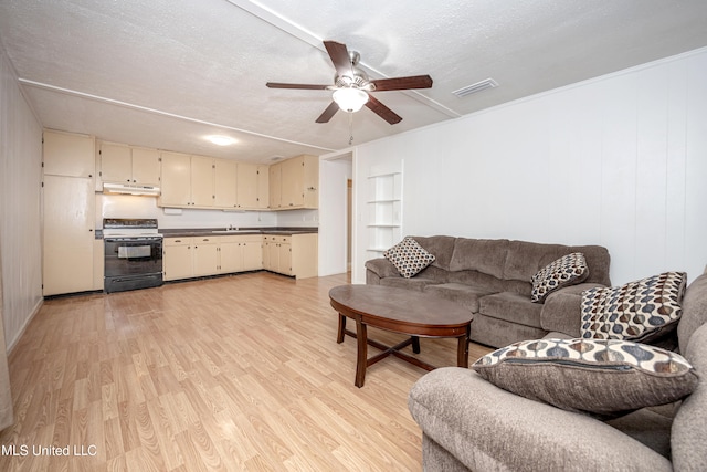 living room with sink, wooden walls, light hardwood / wood-style flooring, ceiling fan, and a textured ceiling