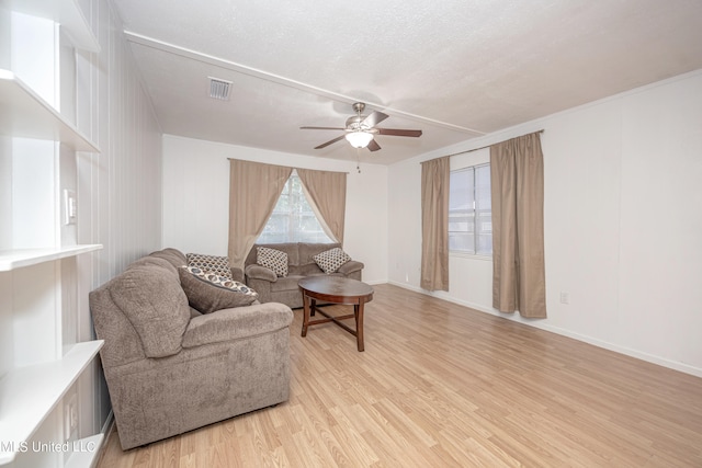 living room with ceiling fan, crown molding, light hardwood / wood-style floors, and a textured ceiling