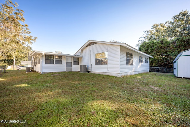 back of property with central AC, a yard, and a shed