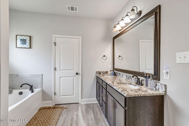 bathroom featuring a tub, vanity, and wood-type flooring