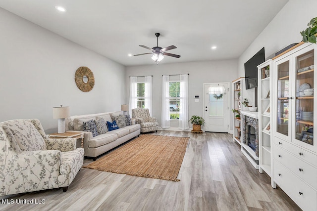 living room with ceiling fan, wood-type flooring, and a fireplace