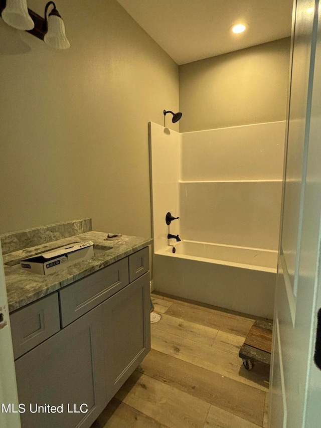 bathroom featuring shower / bathtub combination, wood-type flooring, and vanity