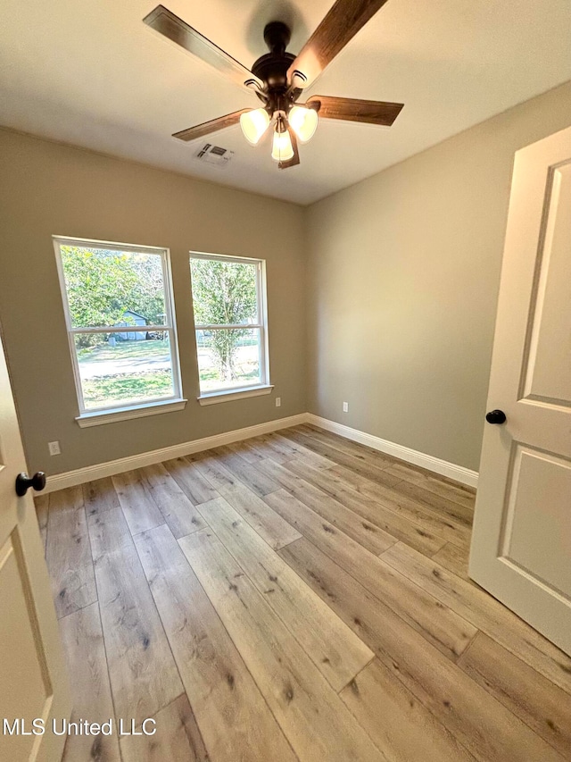 unfurnished room featuring a healthy amount of sunlight, ceiling fan, and light hardwood / wood-style flooring