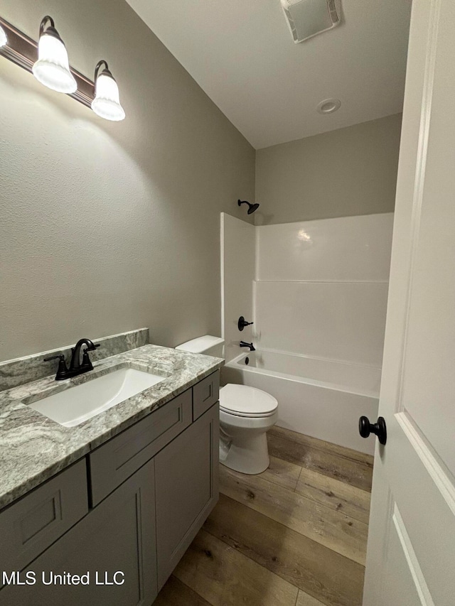 full bathroom with shower / tub combination, vanity, hardwood / wood-style floors, and toilet