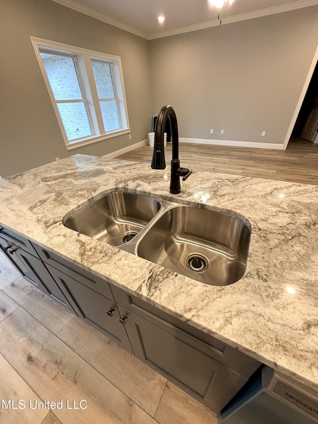 kitchen featuring crown molding, sink, light stone counters, and light wood-type flooring