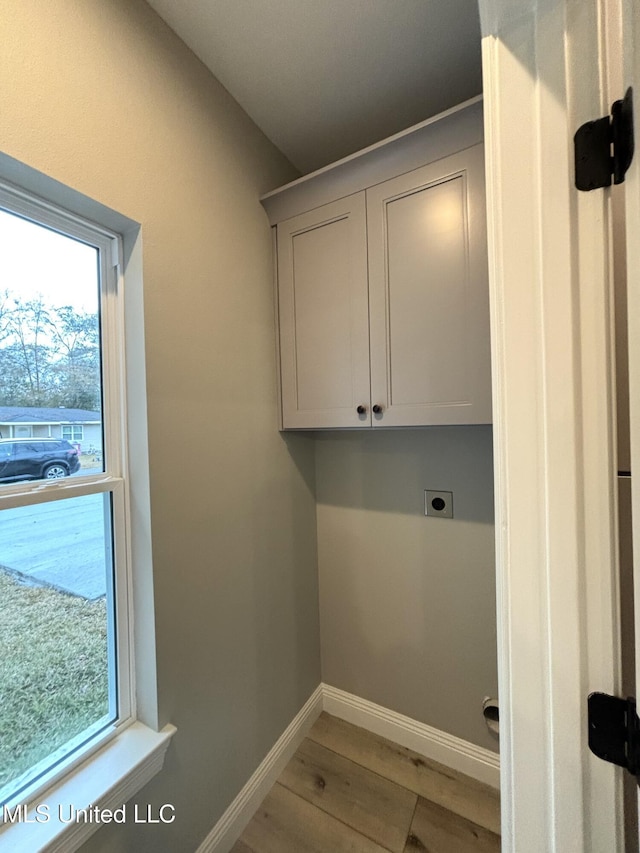 laundry area with cabinets, hardwood / wood-style floors, plenty of natural light, and hookup for an electric dryer