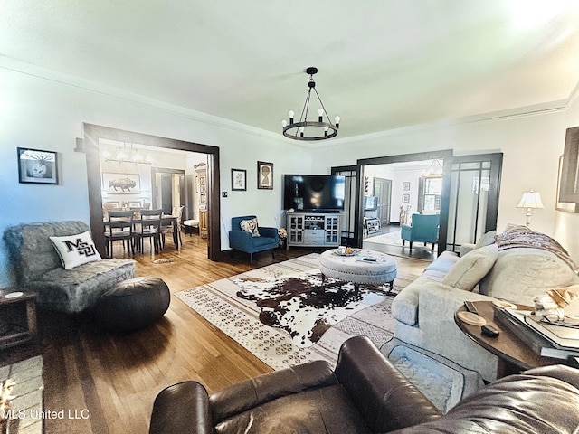 living room with light hardwood / wood-style floors, ornamental molding, and a chandelier