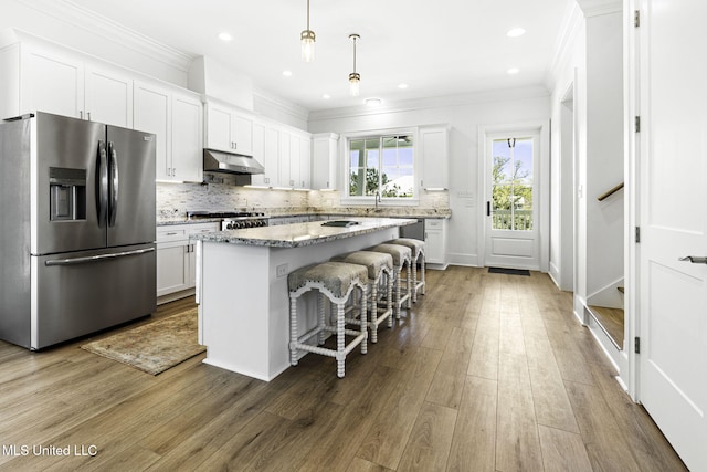 211 Chartres St, Bay Saint Louis, MS 39520 - kitchen with stainless steel fridge with ice dispenser, a center island, ornamental molding, white cabinets, and under cabinet range hood