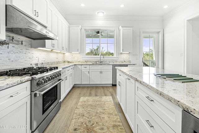 211 Chartres St, Bay Saint Louis, MS 39520 - kitchen with stainless steel appliances, under cabinet range hood, a sink, light wood-style floors, and white cabinetry
