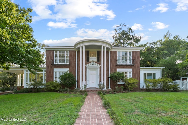 neoclassical home featuring a front lawn