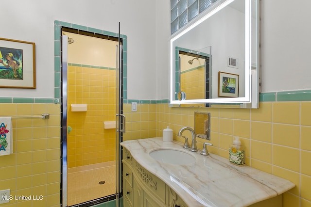 bathroom featuring vanity, walk in shower, and tile walls