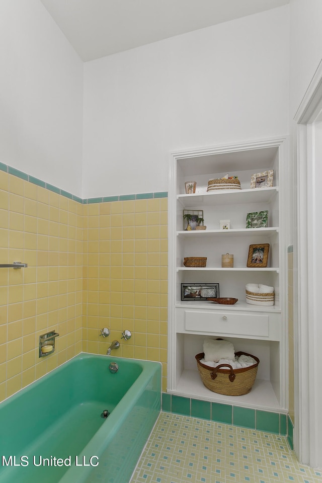 bathroom with tile walls, a tub to relax in, and tile patterned flooring