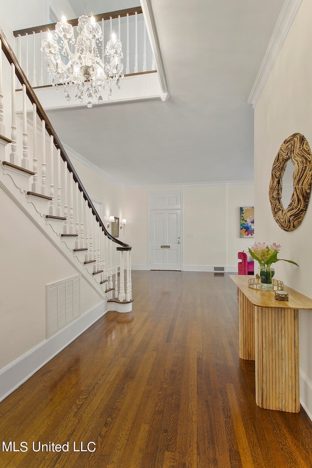 foyer with crown molding, a notable chandelier, and dark hardwood / wood-style floors