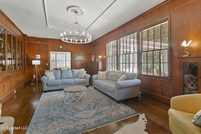 living room with wooden walls, dark hardwood / wood-style floors, and a chandelier