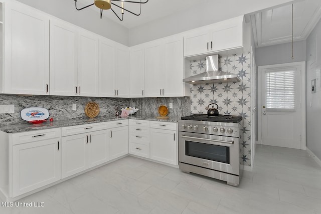 kitchen featuring wall chimney range hood, backsplash, stone countertops, high end range, and white cabinetry