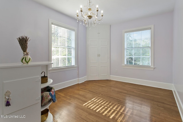 spare room featuring wood-type flooring and an inviting chandelier