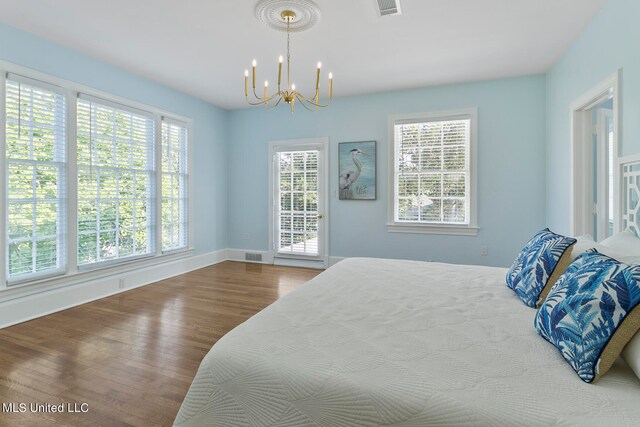 bedroom with a notable chandelier, multiple windows, and hardwood / wood-style flooring