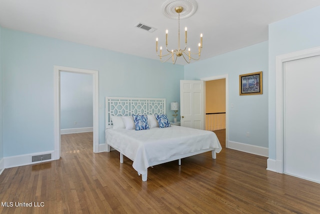 bedroom with dark hardwood / wood-style floors and an inviting chandelier