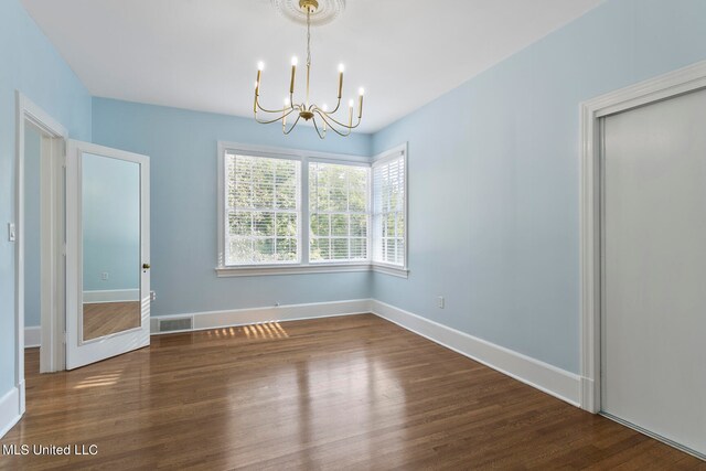 empty room featuring an inviting chandelier and dark wood-type flooring